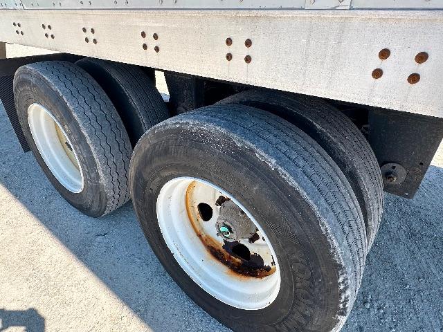 Two rear dual tires on a trailer with white steel wheels and visible rust around the brake drum area.