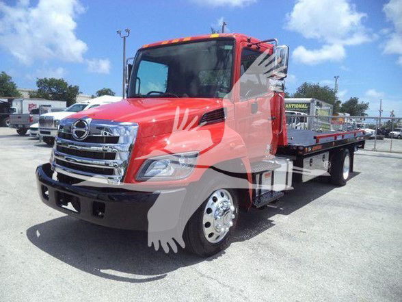 Tow truck identification: red 2020 Hino 268A with flatbed, side view, chrome front grille, dual rear wheels, daylight.