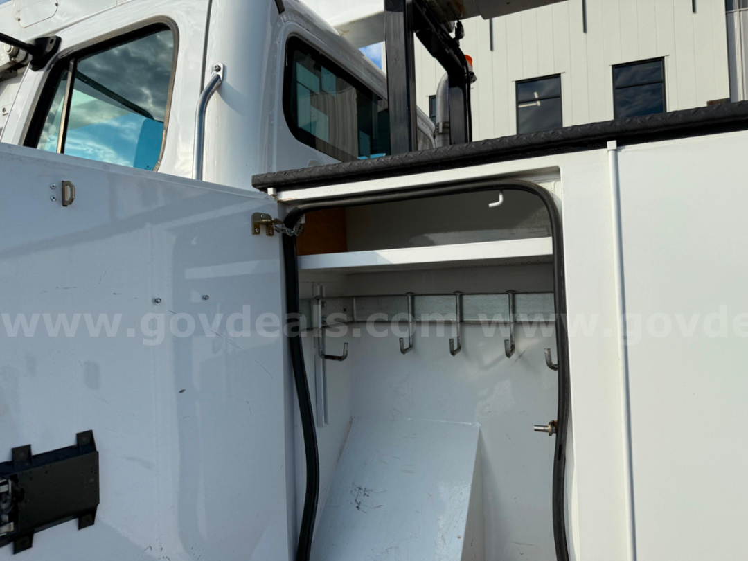 Truck body interior showing storage cabinet with hooks and shelves inside a Freightliner TEREX TC-55 bucket truck.