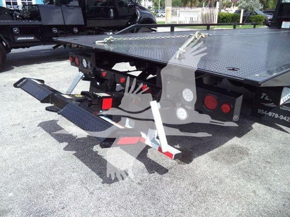 Flatbed tow truck rear with hydraulic wheel lift and chrome tie-downs, platform with diamond plate texture.