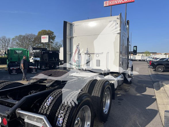 Kenworth T880 truck cab and rear wheels visible in a dealership lot. Exterior shows chrome fuel tanks and dual rear axles. Some text on the truck and scene in background.