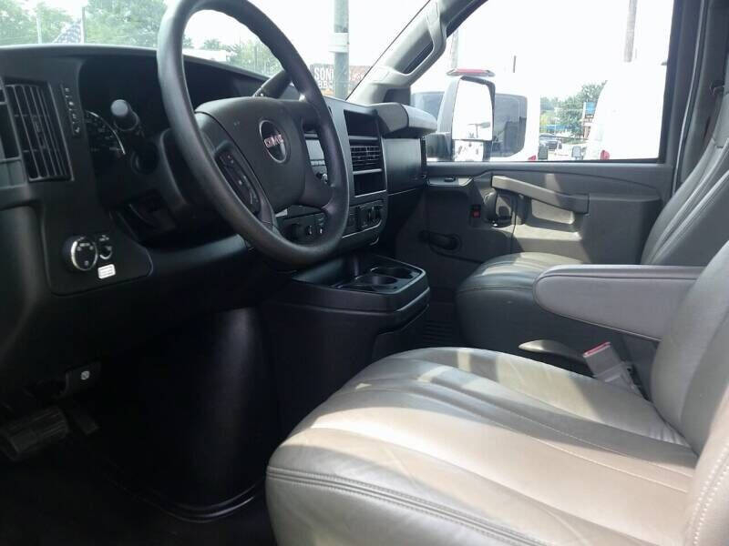 GMC Savana 3500 interior front seats and dashboard view showing steering wheel, center console, and passenger seat.