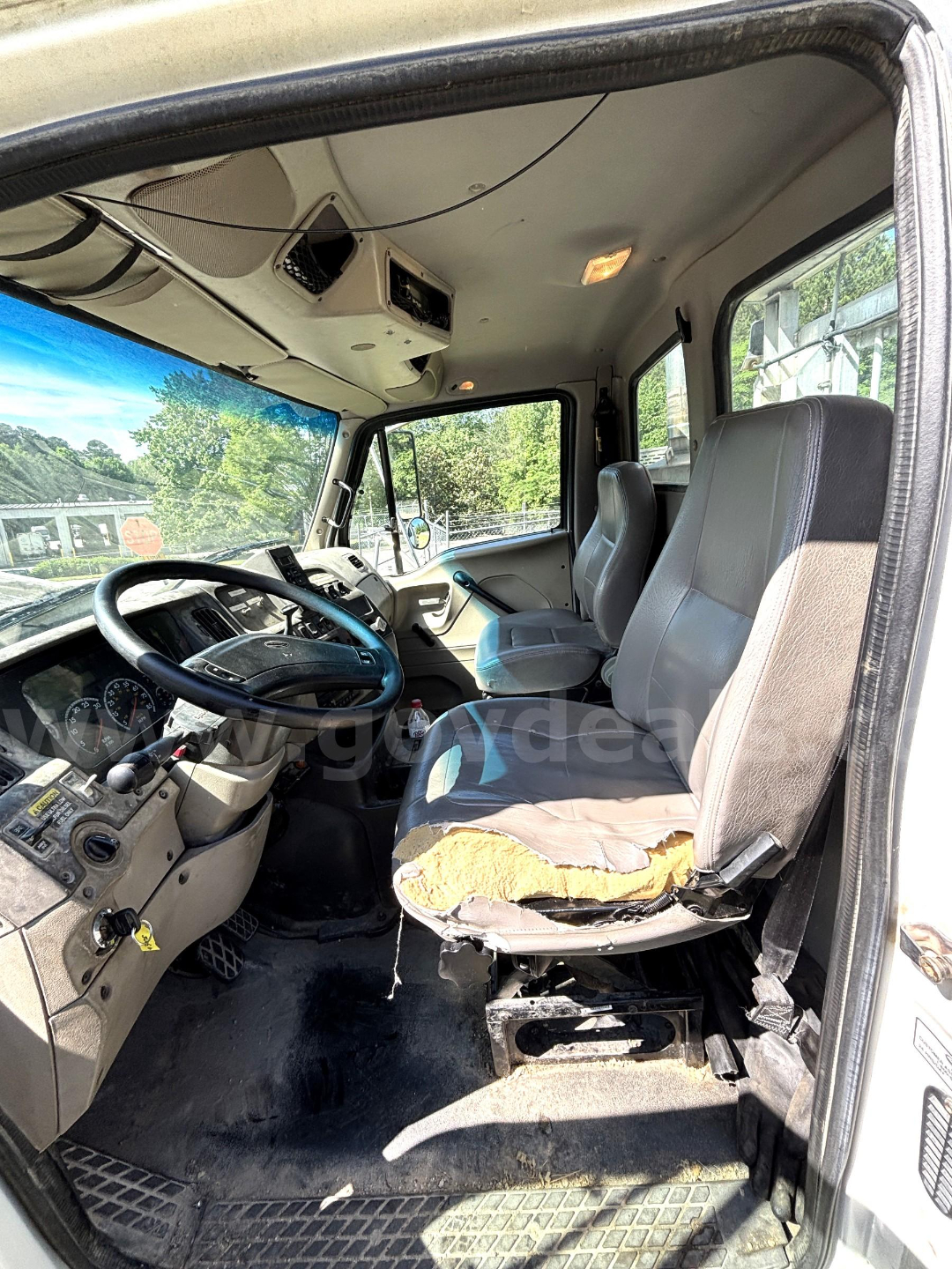 Cab and Chassis truck interior showing steering wheel, driver seat with torn upholstery, dashboard with gauges, and overhead storage.