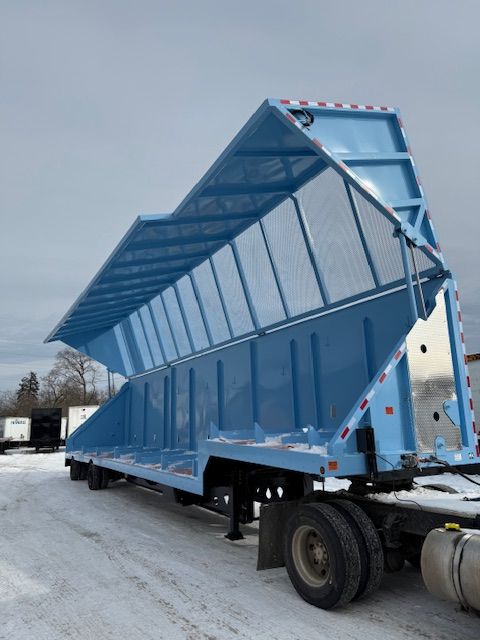 Crush car trailer with blue steel bed and side walls, 48 ft length, on a snow-covered lot.