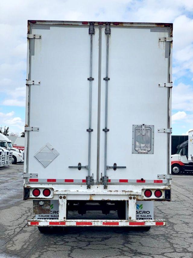 Rear view of a white 2009 Stoughton dry van trailer with double hinged rear doors, recessed door handles, and a small side access door on the right door. Red and white reflective tape along the lower edge; bumper with taillights and license