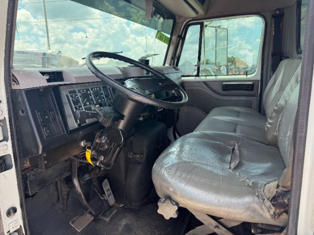 Interior of a 1999 International 4700 DT 466E cab showing steering wheel and bench seat.