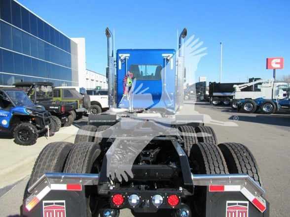 Kenworth W900L tractor rear view showing fifth wheel, dual rear axles, and trailer connections at a truck dealership lot.