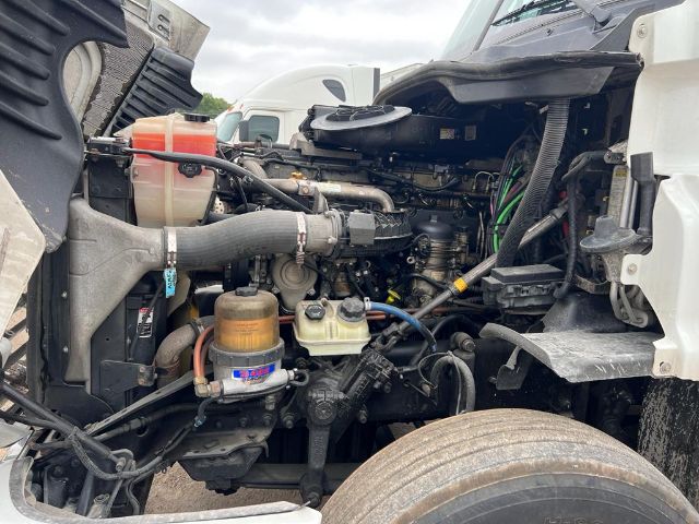 View of a Freightliner Cascadia engine bay with hoses, reservoirs, and components visible; coolant reservoir, air intake, and fuel filter are identifiable.