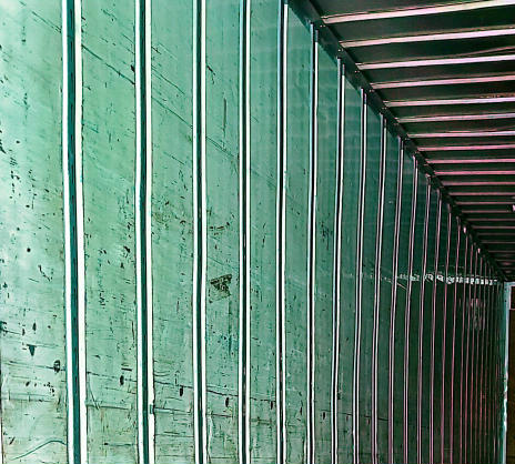 Interior of a trailer showing ribbed metal wall with light green paint and vertical support ribs.