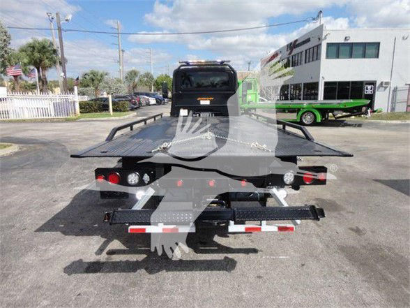 Tow truck flatbed rear showing loading winch and taillights, with truck bed and rear bumper visible.