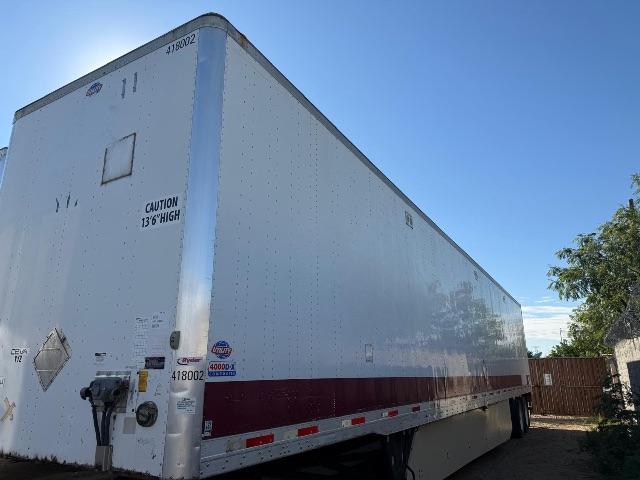 Utility trailer 2012 4000DX side and rear view showing white aluminum exterior with maroon stripe, CAUTION 13'6" HIGH label, various stickers, and rear doors.