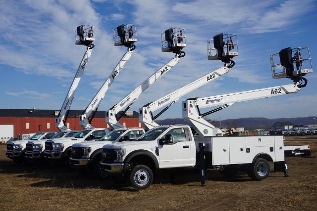 Ford F-550 bucket trucks with Manitex A62 aerial lifts, white crew cab chassis parked in row under blue sky.