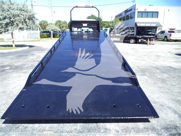 Tow truck flatbed with Isuzu FTR branding; no explicit text visible on the bed surface aside from a large graphic of a white bird or dove stretched across the bed.