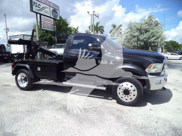 2018 Ram 4500 SLT tow truck with flatbed, side view shows large side mirrors, black body, chrome bumper. Visible text on window and sign: dealership lot in background.