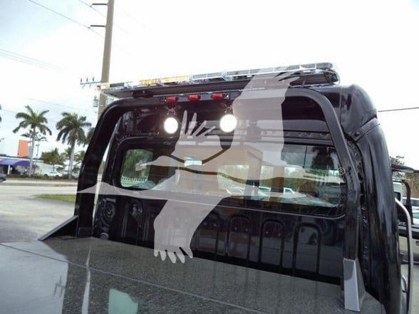 Back view of a new 2025 Freightliner Business Class M2 106 truck with a cargo bed and rear window, showing a roof light bar and headliner reflections.
