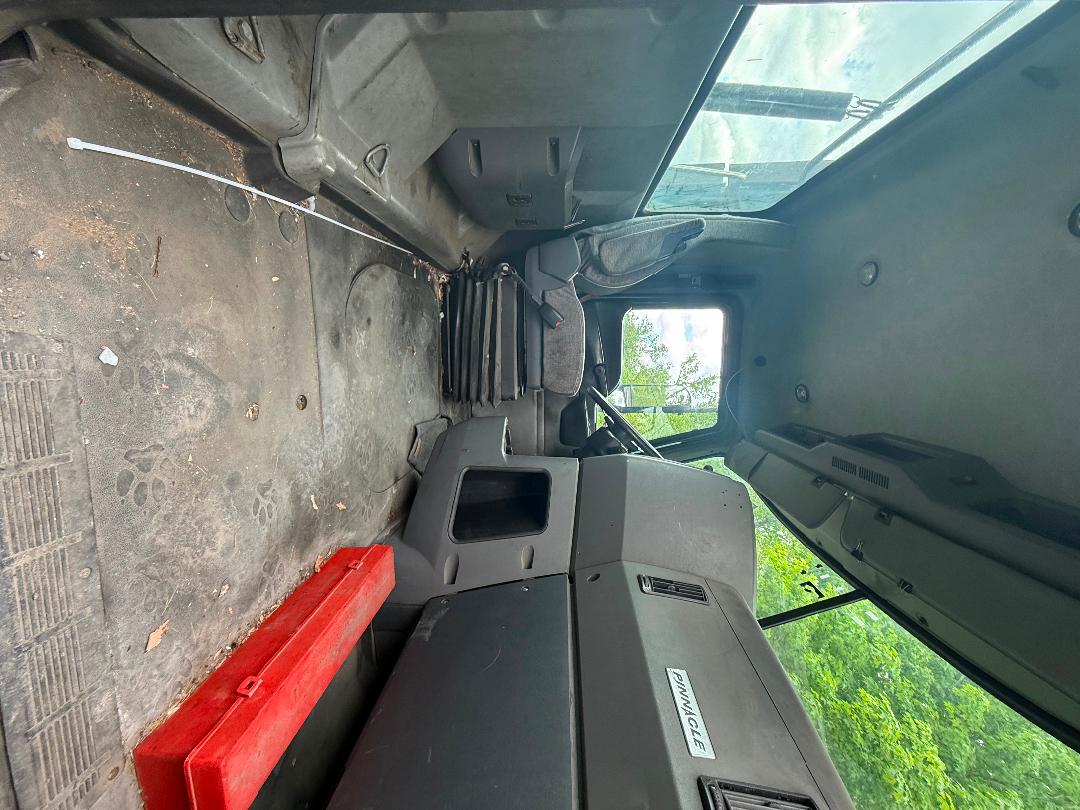 Cab interior of a 2016 Mack CXU 612 truck showing dashboard, steering wheel, floor with dirt, and a red toolbox along the passenger side.