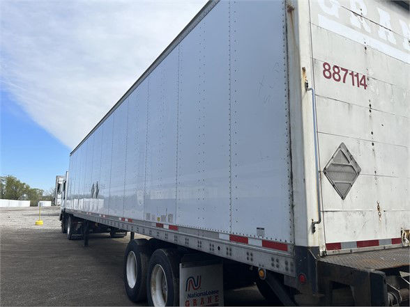 Long white Wabash dry van trailer with red stock number 887114 on rear door, viewed from side in a trailer yard.