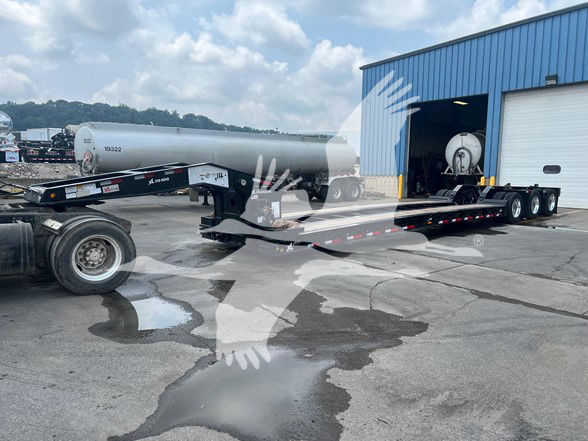 XL Specialized XL110HDGS18 lowboy trailer in front of a blue building, tanker trailer visible, long flatbed with dual rear axles and gooseneck, VIN 4U3J05331TL024324 on image watermark
