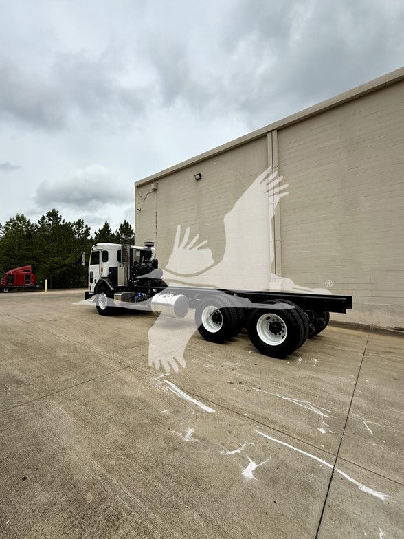 Kenworth L770 cab and chassis truck in an outdoor lot showing the rear flatbed and dual rear axles.
