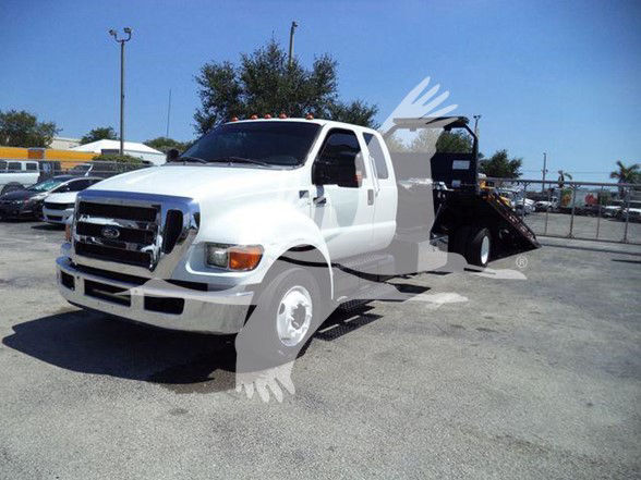 2015 Ford F650 XLT tow truck with white cab and black flatbed. Visible text includes Ford front grille and general truck features.