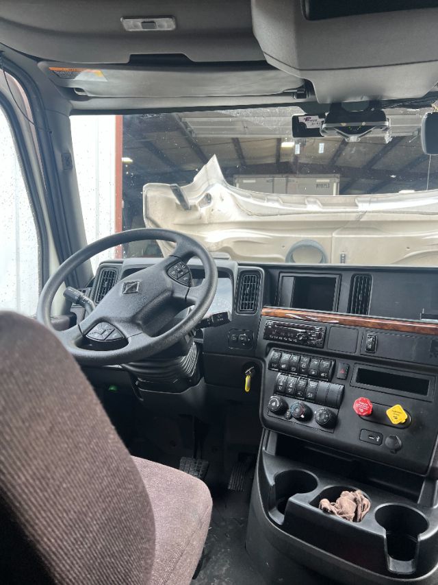 Truck cab interior with steering wheel, dashboard, and center console of a 2019 International LT625 conventional sleeper.