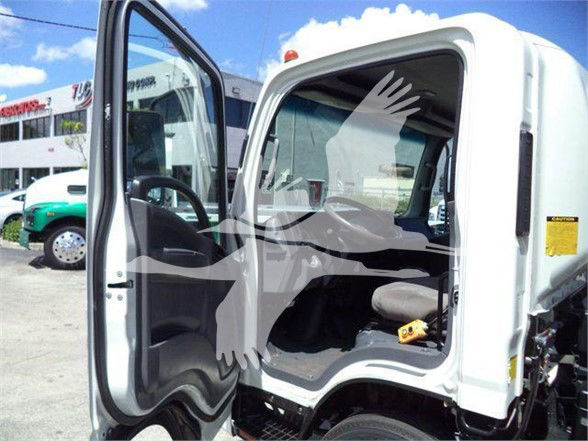 Isuzu NRR cab interior with open door showing steering wheel, dashboard, and passenger seat; white truck body with yellow safety sticker on door frame.