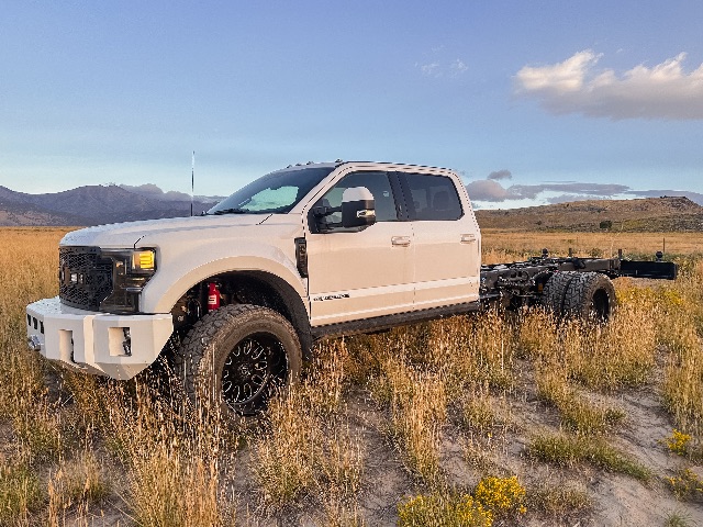 2022 Ford F-550 Lariat cab and chassis truck in a field, white exterior, dual rear wheels, off-road tires, with chassis behind the cab.
