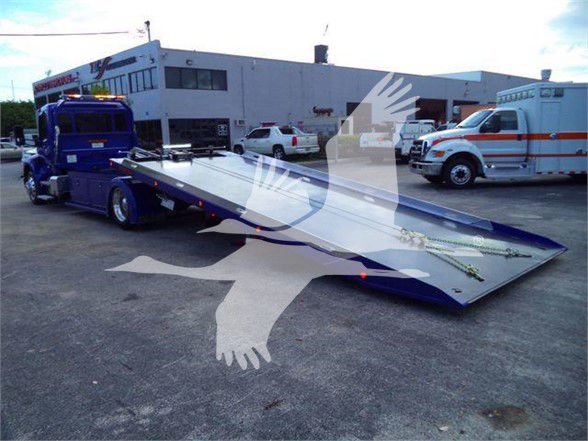 Tow truck with a long blue flatbed in a parking lot, Peterbilt 536, stock BLUE536STEPSIDE, tow category, new unit.