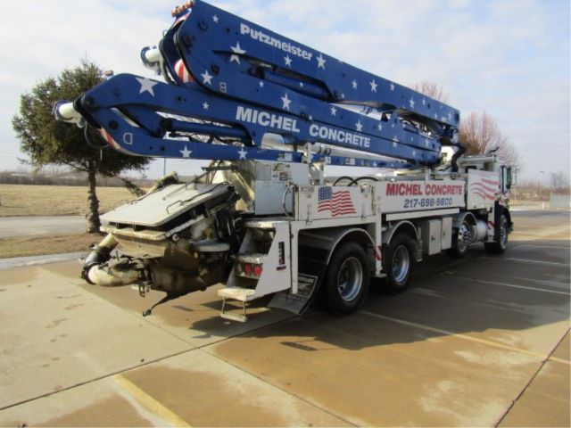 Large tow truck with a blue concrete pump arm labeled Michel Concrete and Putzmeister on a white truck chassis.