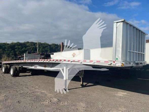 Flatbed trailer with a drop-deck style front and a large aluminum ramp/chute at the rear, 3-axle configuration, white paint, in-service condition.