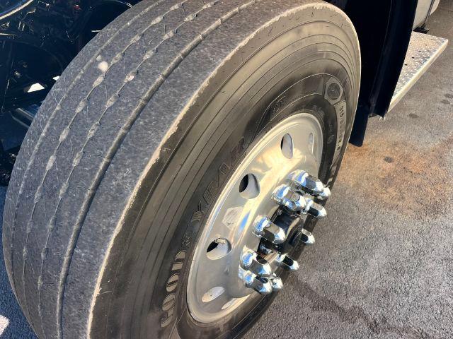 Truck wheel and tire close-up showing dual rear hub with chrome lug nuts and Goodyear tire on Freightliner M2 series.