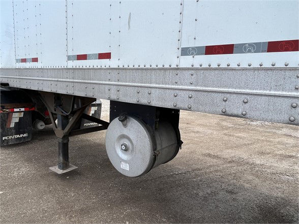 Great Dane dry van trailer side showing mudflaps and a circular air tank undercarriage relief valve. Metal riveted panels with reflective tape along edge.
