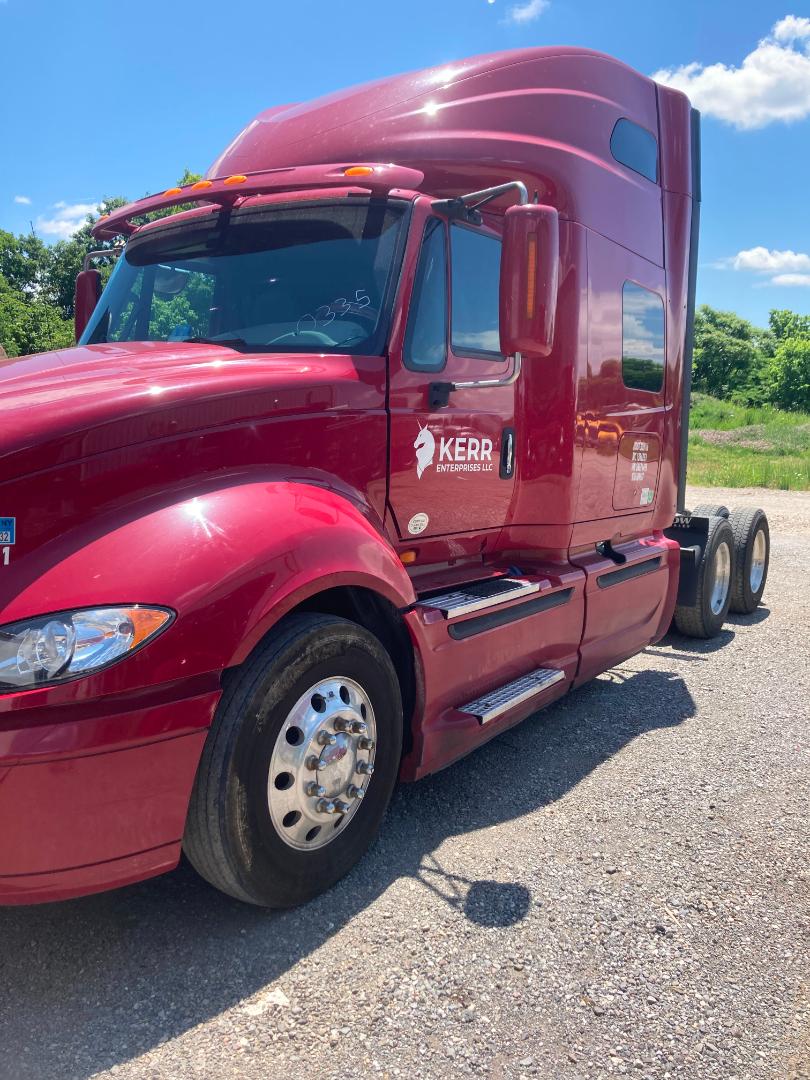 Red 2016 International Prostar tractor cab side view showing Kerr Enterprises LLC logo on door, front wheel, and sleeper cab with chrome steps.