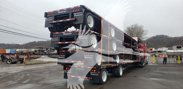 Transcraft DTL-2100 trailer stacked on a multi-axle trailer, with brand labels visible on the rear and sides.
