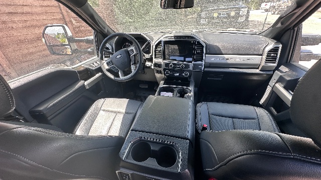 Truck cabin interior showing steering wheel, center console, touchscreen display, and front seats of a 2022 Ford F-550 Lariat.