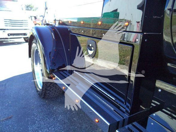 Image shows a sleek black 2023 International CV truck side panel with glossy finish and orange marker lights along the top edge.