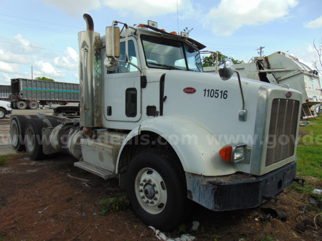 Peterbilt 365 cab and chassis front-right side view with white paint, large grille, exhaust stack, and dual rear axles.,” showing 110516 number on door and cab details.
