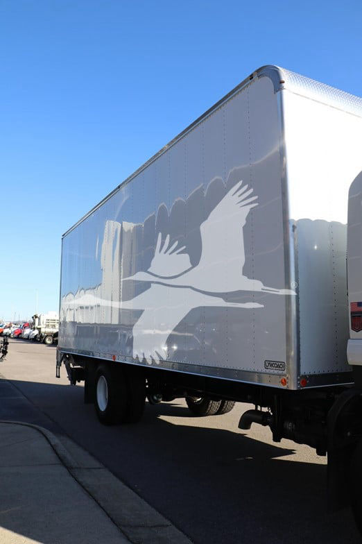 Isuzu FTR box truck trailer with white eagle graphic on side, rear view showing side of cargo box and wheel wells.