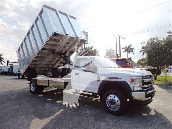 Ford F-Series chassis cab with a lifted hydraulic dump bed in a dealership lot. No visible labels or text on components readable in the image.