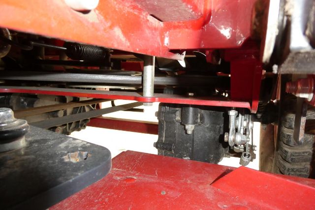 Ferris IS 700Z undercarriage showing drive components and red chassis; black motor or hydraulic unit near center, metal tubing, and wheel in background.