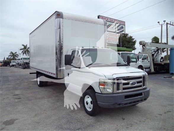 Ford E-Series box truck with a large cargo box, front grille, and side mirrors. Vehicle shown in a used truck lot.