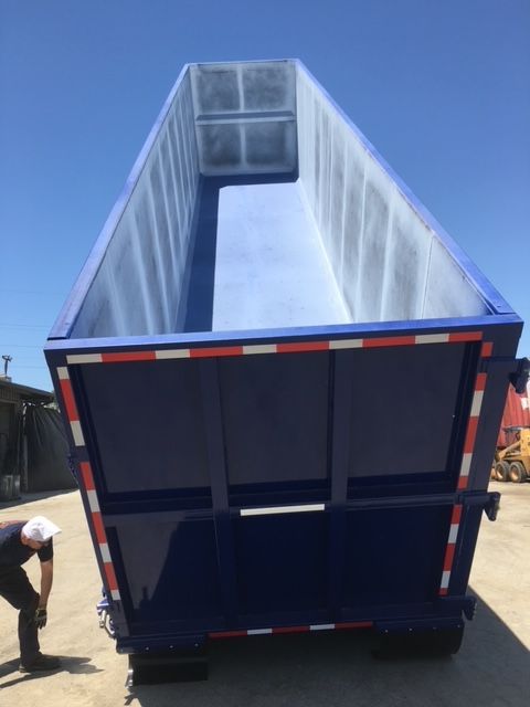 Blue 40 ft dump trailer with open bed showing interior walls and rear gate, utility trailer in a lot.