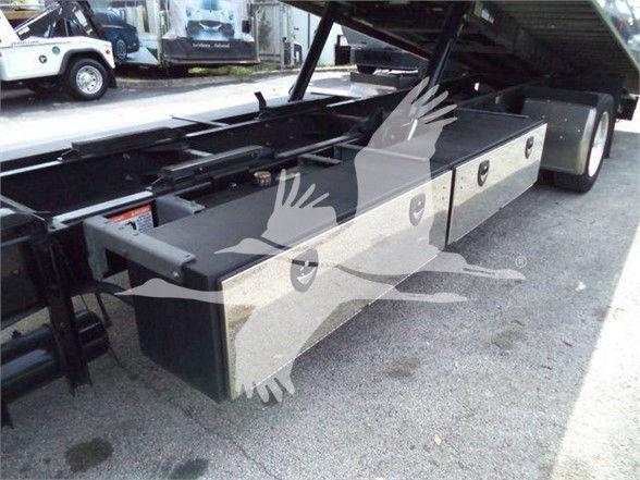 Kenworth T370 tow truck chassis with flatbed and storage boxes on the side; raised bed with hydraulic mechanism visible. Gas/oil/dot labels not clearly legible.