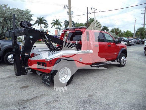 Ram 5500 tow truck with red cab and black tow boom, flatbed utility equipment visible.