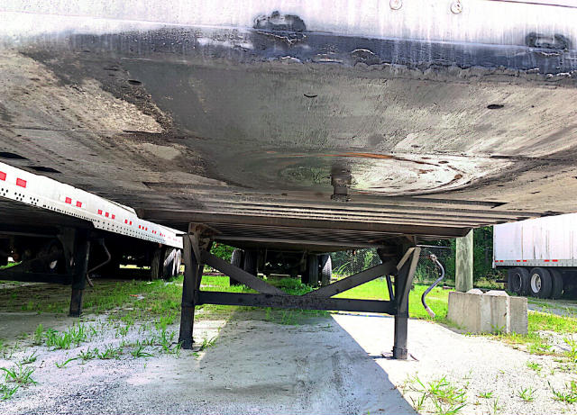 Trailer undercarriage showing support legs and underside of Vanguard VXP trailer with metal frame and tires in background.