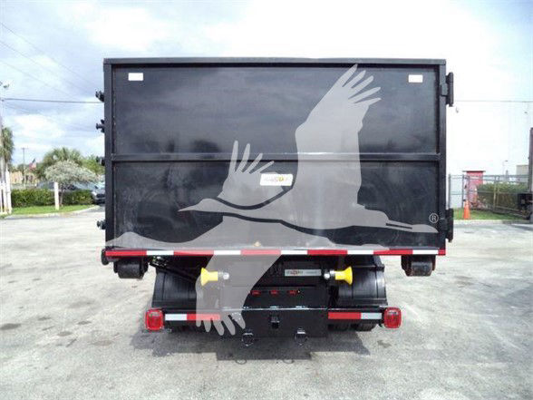 Rear view of a 2023 Chevrolet Silverado 6500HD dump truck with a black bed and yellow hitch components.