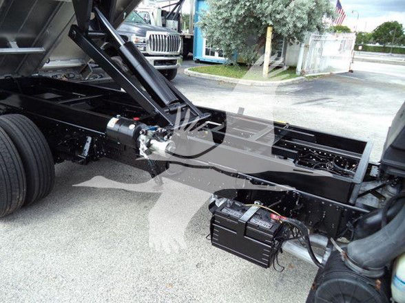 Chevrolet W4500 dump truck chassis showing mounted battery/distribution box and hydraulic lines with frame rails.