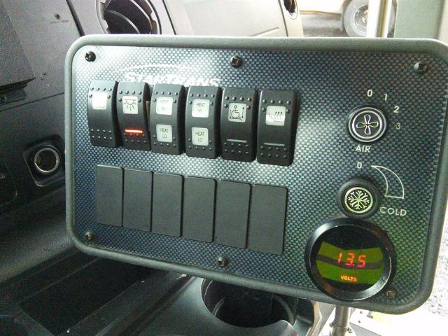 Dashboard panel with multiple switches and a digital volt meter showing 13.5 volts.