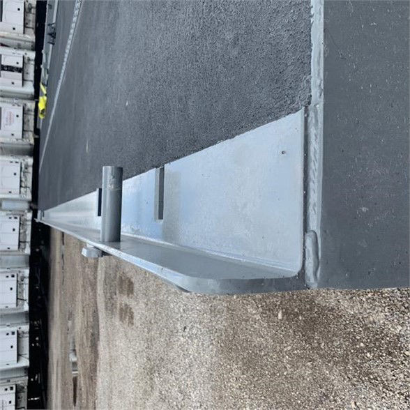 Container delivery trailer edge with tanDEM axle and side skirt; visible metal lip and stake pocket along the side.