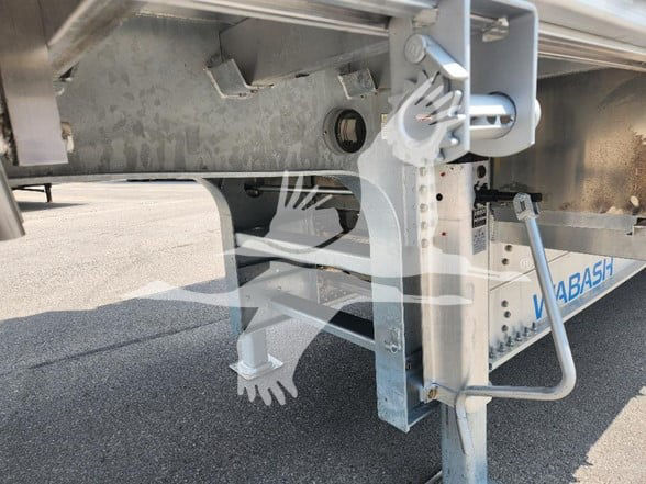 Trailer undercarriage showing support legs, frame, and hitch hardware of a Wabash drop deck trailer.
